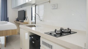 A modern kitchen with a built-in stove, sink, and a small countertop. - Stunning Studio Apartment at Sky House BSD (Pagedangan)