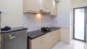A kitchen with light wooden cabinets, a black countertop, a built-in microwave, and a gas stove. - Nice and Comfy 1BR Apartment at MT Haryono Residence (Jakarta)