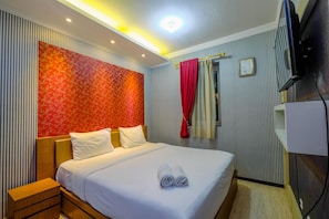 Une chambre d’hôtel avec un lit, une table de chevet, une télévision et un rideau.