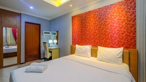 A hotel room with a large bed, a desk, a chair, and a wardrobe. - Lush 3BR Residence at Grand Palace Kemayoran (Jakarta)