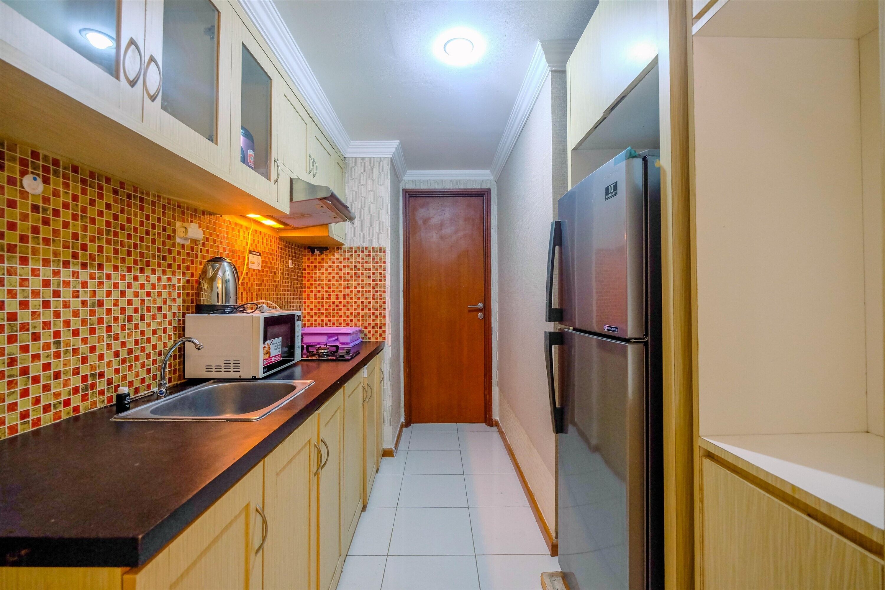 Una cocina pequeña con un lavaplatos, microondas y refrigerador.