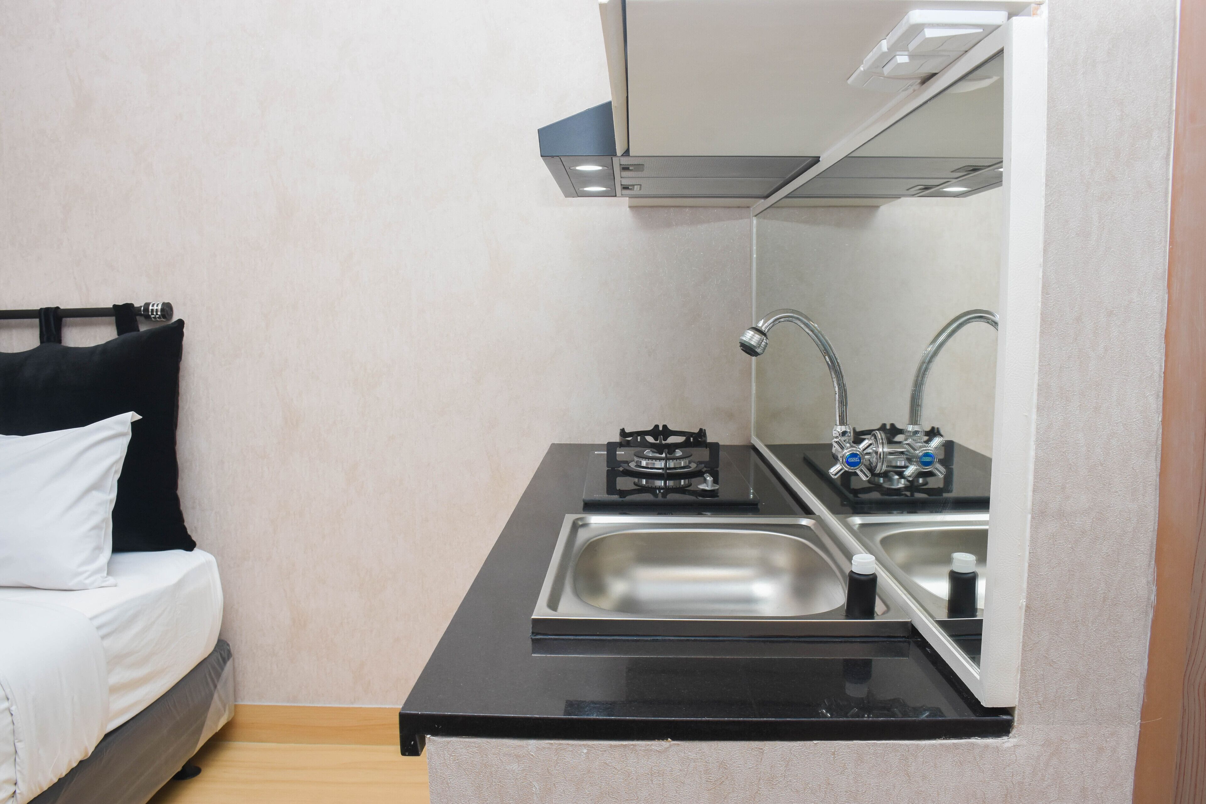A compact kitchenette with a sink, stove, and mirror.