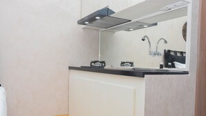 A compact kitchen with a black countertop, white cabinets, and a stainless steel range hood. - Fancy and Nice Studio at Cinere Resort Apartment (Depok)