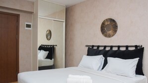 A hotel room with a bed, a wardrobe, a mirror, and a wall decoration. - Fancy and Nice Studio at Cinere Resort Apartment (Depok)