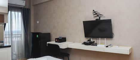 Une chambre d’hôtel équipée d’un lit, d’un bureau avec un ordinateur, d’une télévision et d’un mini-bar.