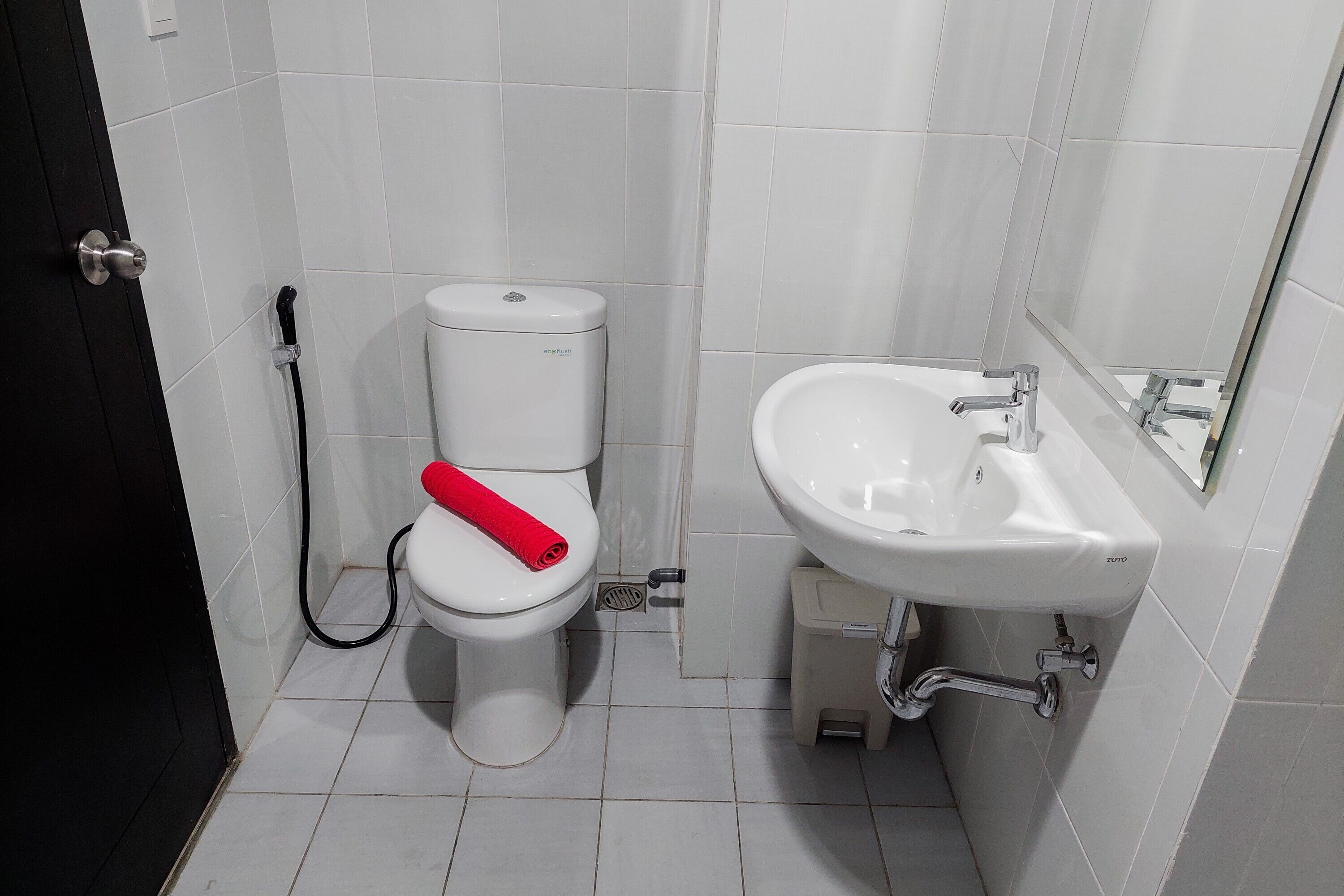 A bathroom with a toilet, a sink, and a mirror.