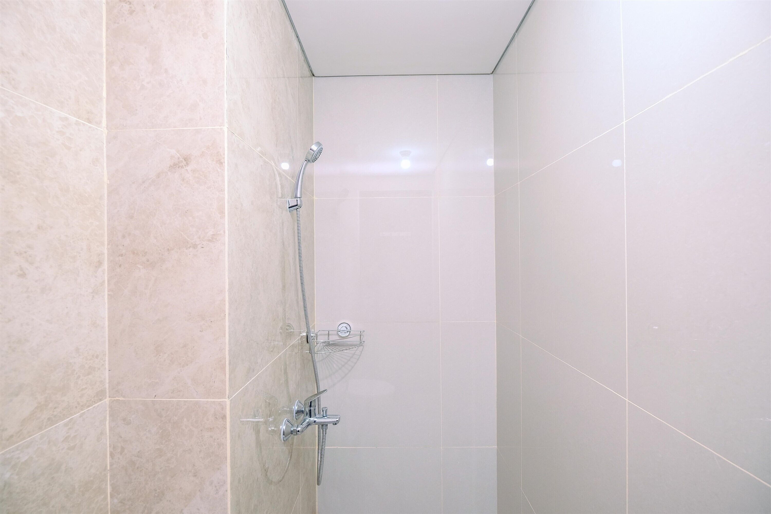 Une salle de bain avec une douche, des murs carrelés et un luminaire au plafond.