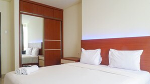Een hotelkamer met een groot bed, een houten garderobe en een spiegel.