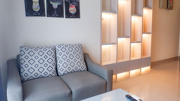 Een moderne woonkamer met een grijze bank, decoratieve kussens en kunst aan de muur met cocktailafbeeldingen.