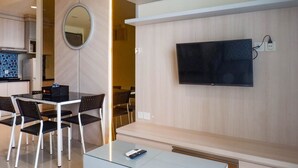 Een moderne hotelkamer met een zithoek, een flatscreen televisie aan de muur en een kleine tafel met stoelen.