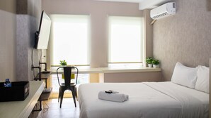 A hotel room with a bed, desk, chair, and two windows. - New and Cozy Studio at Patraland Urbano Apartment (Bekasi)