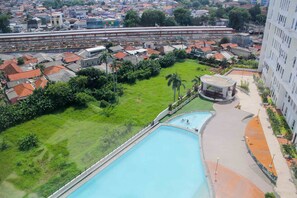A hotel with a swimming pool, a green lawn, and a view of the surrounding cityscape.