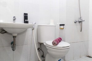 A bathroom with a white sink, toilet, and shower. - New and Cozy Studio at Patraland Urbano Apartment (Bekasi)