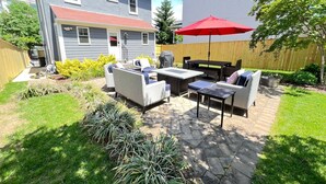 A patio area with outdoor furniture, a red umbrella, and a stone pathway. - Recently Renovated Annapolis Home - Conveniently Located (Annapolis)