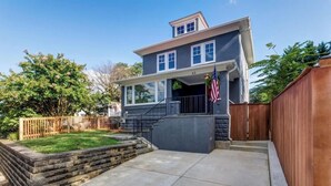 A two-story house with a front porch, a stone retaining wall, and a wooden fence. - Recently Renovated Annapolis Home - Conveniently Located (Annapolis)