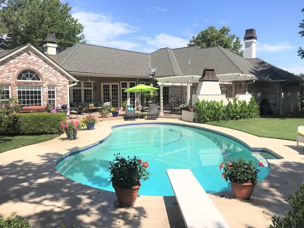 A residential property with a swimming pool, outdoor seating, and a brick house.