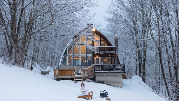 A cabin with a large window, a balcony, and a wooden deck.
