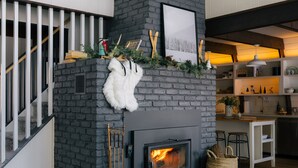 A modern living room with a fireplace, a staircase, and a kitchen area.