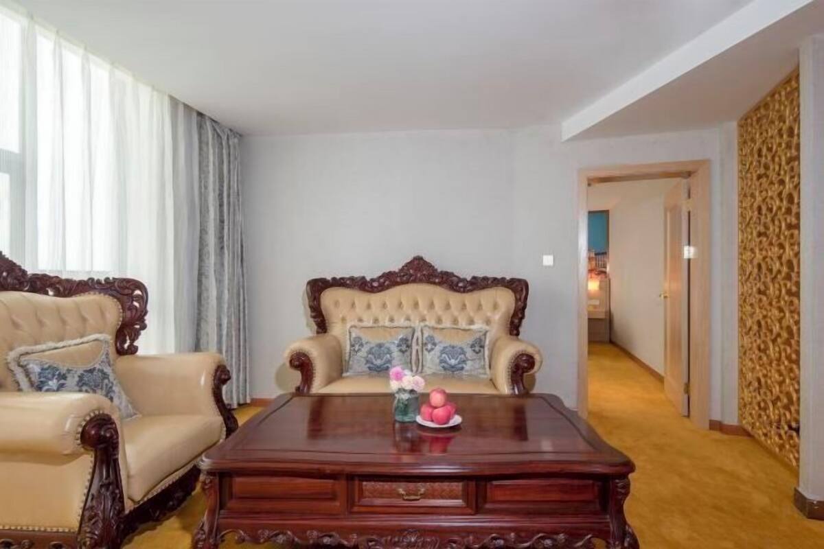 Una habitación con un sofá color beige, un sillón a juego y una mesa de centro de madera con adornos.