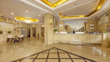 Un vestíbulo de hotel con un mostrador de recepción, una zona de comedor y una mesa de recepción.