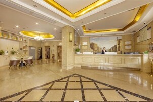 Un vestíbulo de hotel con un mostrador de recepción, una zona de comedor y una mesa de recepción.