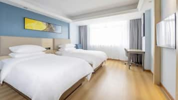 Una habitación de hotel con dos camas, un escritorio y un ventanal grande.