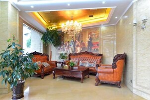 Una hall con un lampadario, divani, un tavolino da caffè e una grande pianta.
