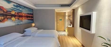 A hotel room with two beds, a painting of a cityscape, a television, and a plant.