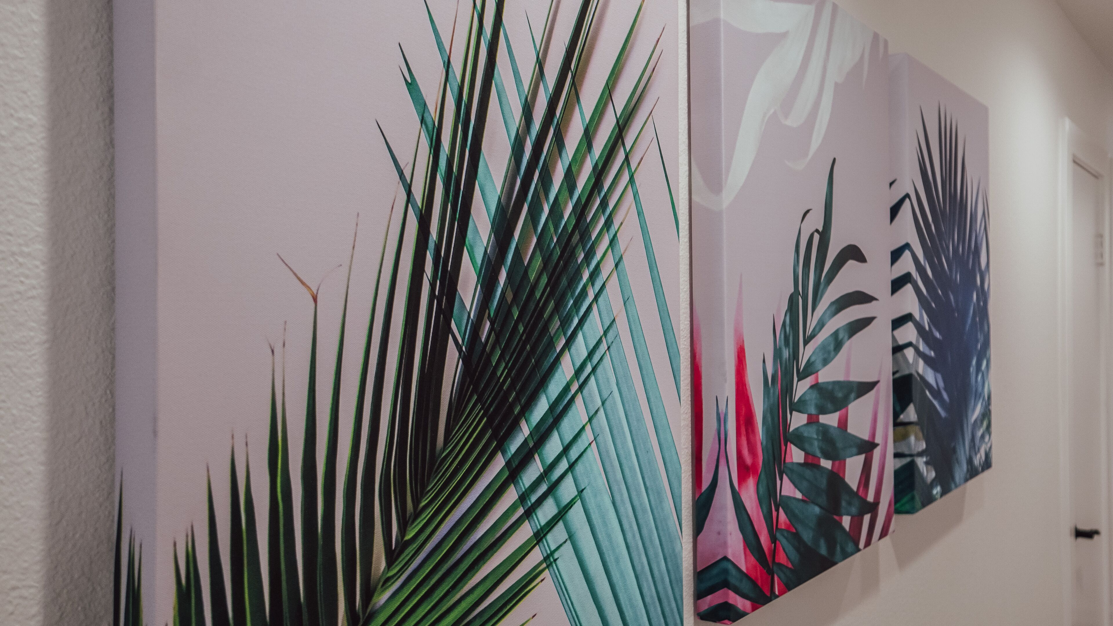A hallway with two large wall-mounted artworks featuring tropical leaves.