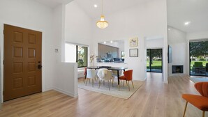 A spacious kitchen with modern appliances, a dining area with a wooden table and chairs, and a large sliding glass door leading to an outdoor patio.