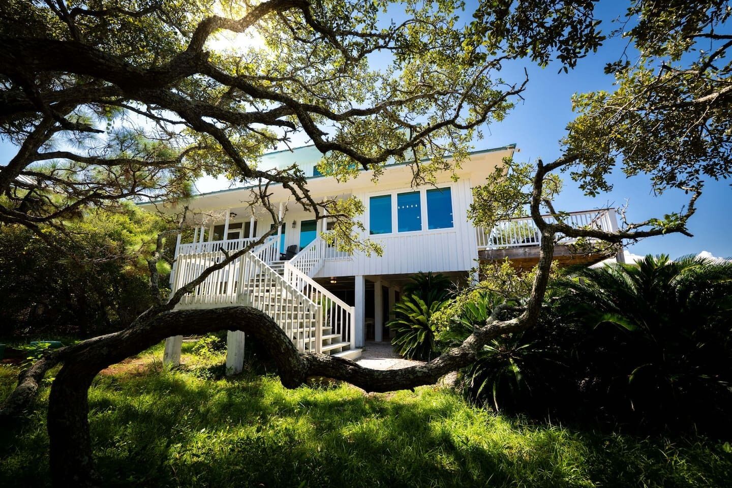 A two-story building with a white exterior, blue windows, and a white staircase leading to the upper level.