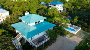 A large house with a blue roof, a deck, and a swimming pool.