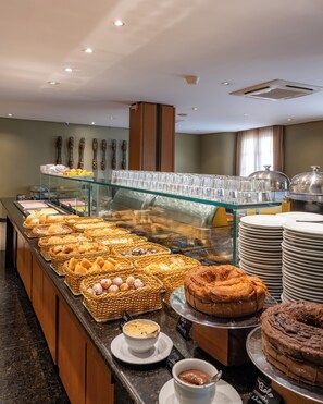 Un buffet proposant une variété de produits de boulangerie, notamment du pain, des viennoiseries et des gâteaux, présentés sur un comptoir séparé des clients par une vitrine.