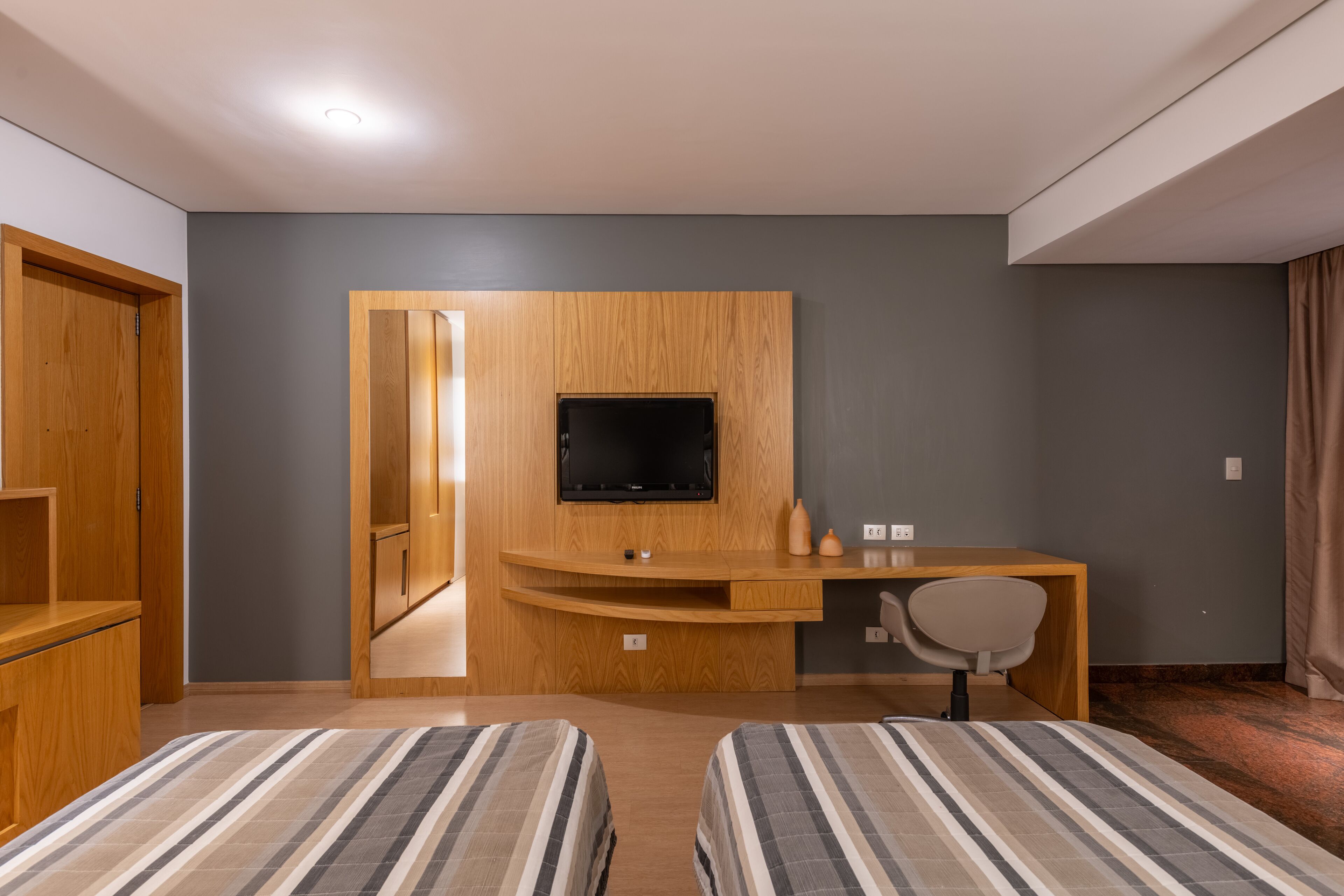 Habitació d'hotel amb dos llits, un escriptori de fusta amb televisió i una cadira.
