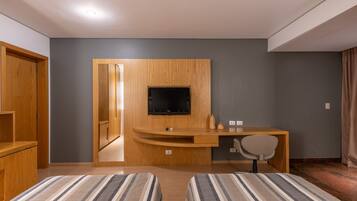 Habitació d'hotel amb dos llits, un escriptori de fusta amb televisió i una cadira.