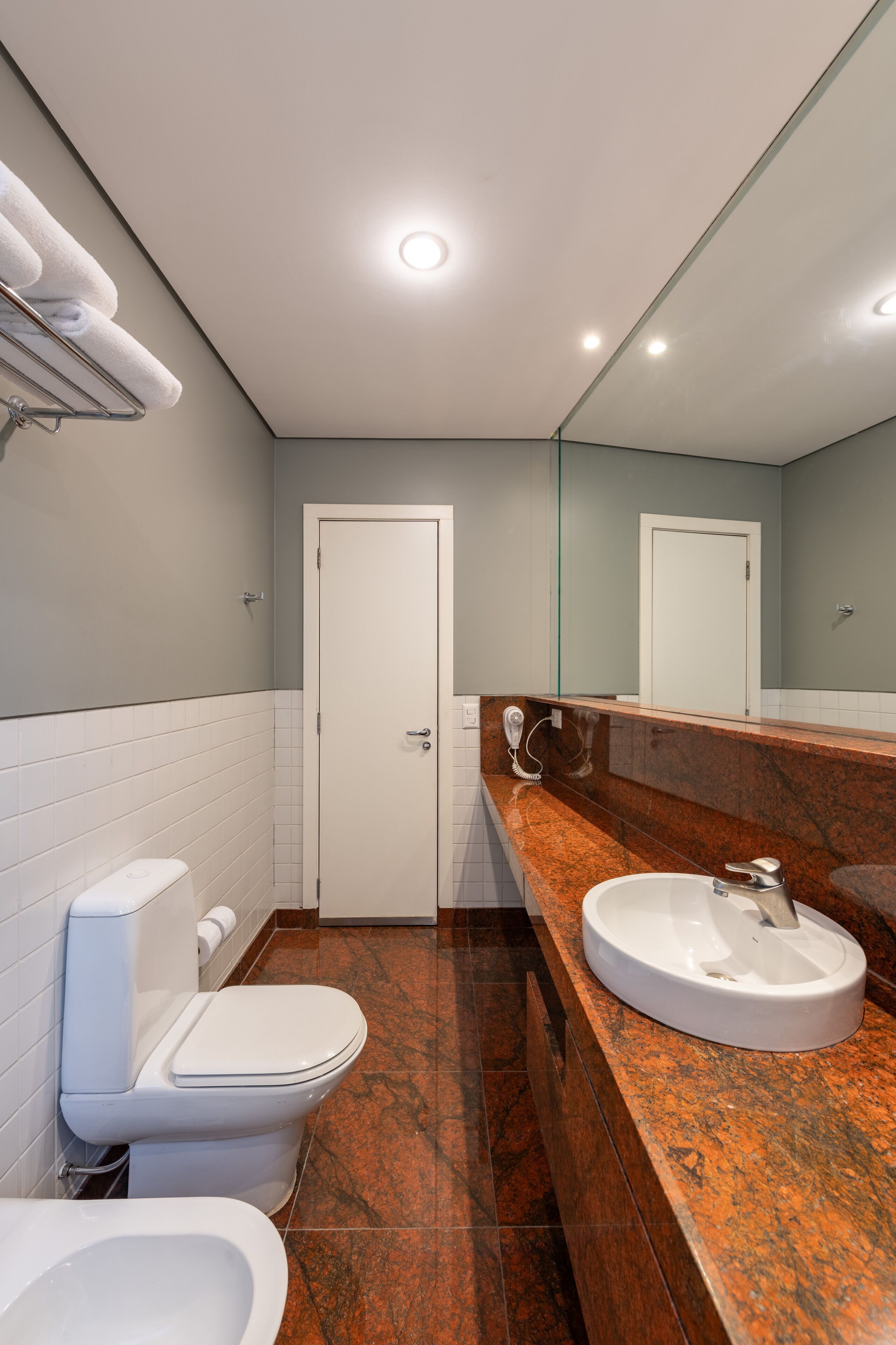 A modern bathroom with a white toilet, a bidet, and a sink with a marble countertop.