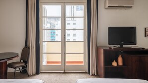 A hotel room with a large sliding glass door, a flat-screen TV on a wooden cabinet, a chair, and a bed. - DELPLAZA Marabá São Paulo (São Paulo)