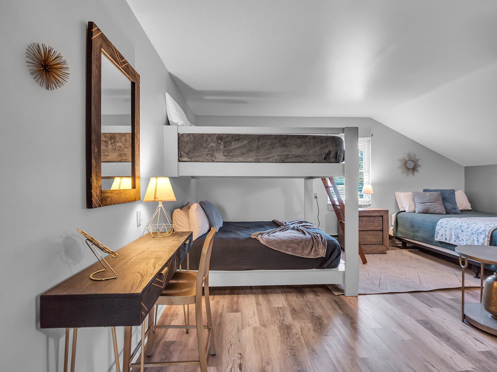 Un dormitorio compacto y moderno con una cama litera, un escritorio con silla y una mesita de noche.