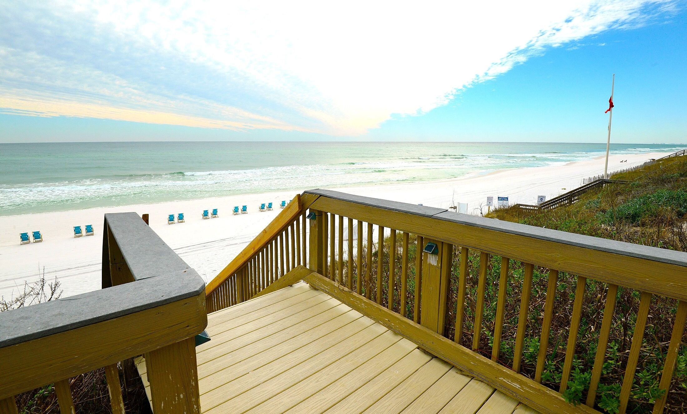 Una terraza de madera con vista a una playa y al océano.