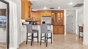 Eine moderne Küche mit Holzausstattung, zwei Barhocker und einem integrierten Kühlschrank.