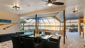 Ein Essbereich mit Blick auf den Pool, Sitzgelegenheiten im Freien und einem Deckenventilator.