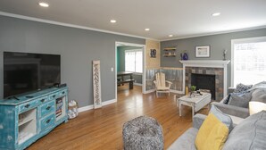 Una sala de estar con televisión de pantalla plana, un mueble azul, un sofá gris y una chimenea.