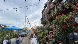 An outdoor seating area with tables and chairs, surrounded by lush greenery and flowering plants. - Lake View Getaway (Benton Harbor)