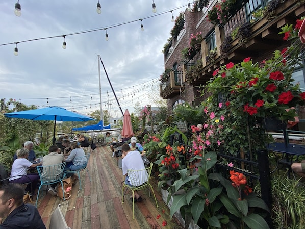 An outdoor seating area with tables and chairs, surrounded by lush greenery and flowering plants. - Lake View Getaway (Benton Harbor)