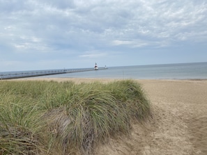 A beach with a pier extending into the water, featuring a lighthouse at the end. - Lake View Getaway (Benton Harbor)