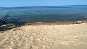 A sandy beach with clear blue water and a few people in the distance. - Lake View Getaway (Benton Harbor)