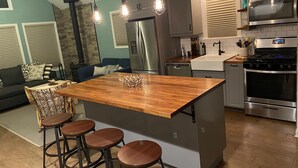 A modern kitchen with a central island, bar stools, stainless steel appliances, and a stone fireplace. - Lake View Getaway (Benton Harbor)