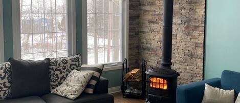 A cozy living room with a stone fireplace, a dark blue sofa, a blue armchair, and a wooden coffee table.