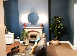 A living room with a fireplace, a sofa, a coffee table, a side table, and a potted plant. - Grand Palace in Gateshead (Gateshead)