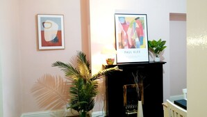 Une pièce avec un piano noir, un tableau abstrait encadré, une lampe et une plante en pot.